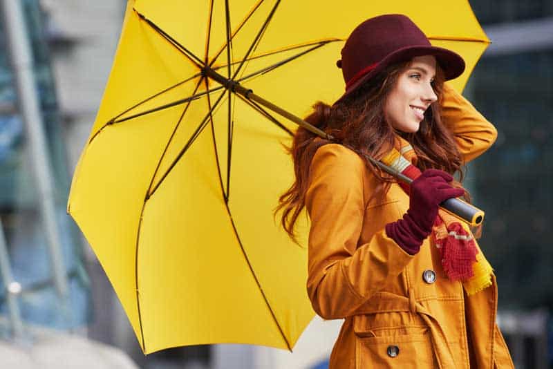Oranger Trenchcoat und gelber Regenschirm für das Herbst-Outfit (depositphotos.com)
